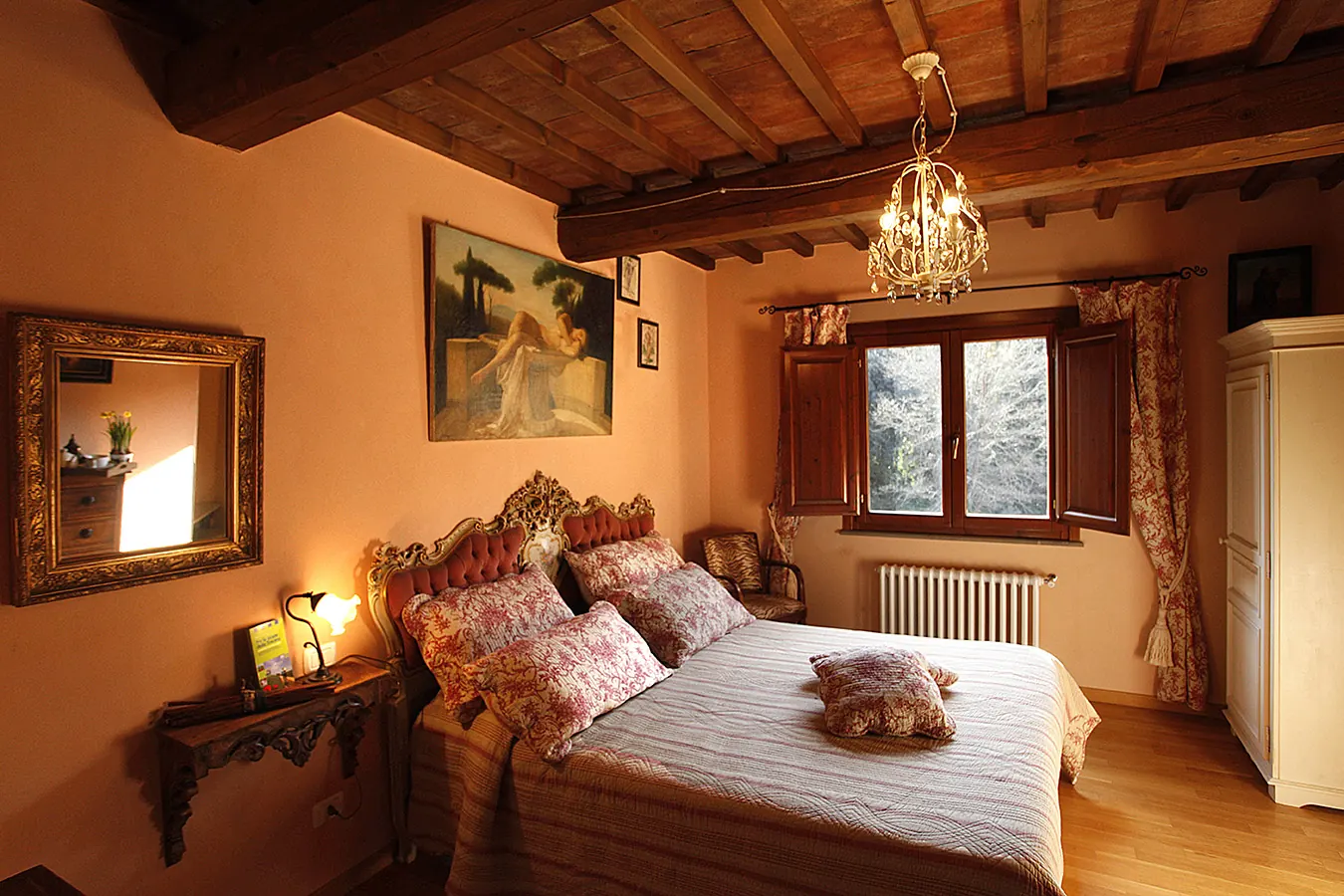 Camera da letto arredata in stile classico con letto matrimoniale, finestra aperta e lampadario