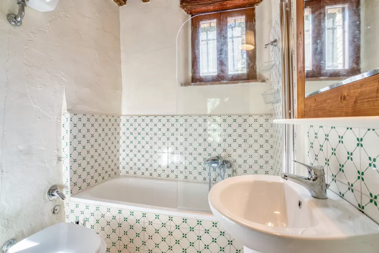 Bathroom with a bathtub, sink, and tiled walls under a window