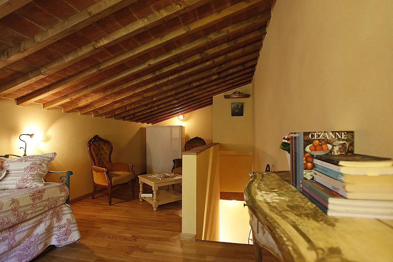 Camera mansardata con letto, poltrone e tavolino in un ambiente caldo e rustico