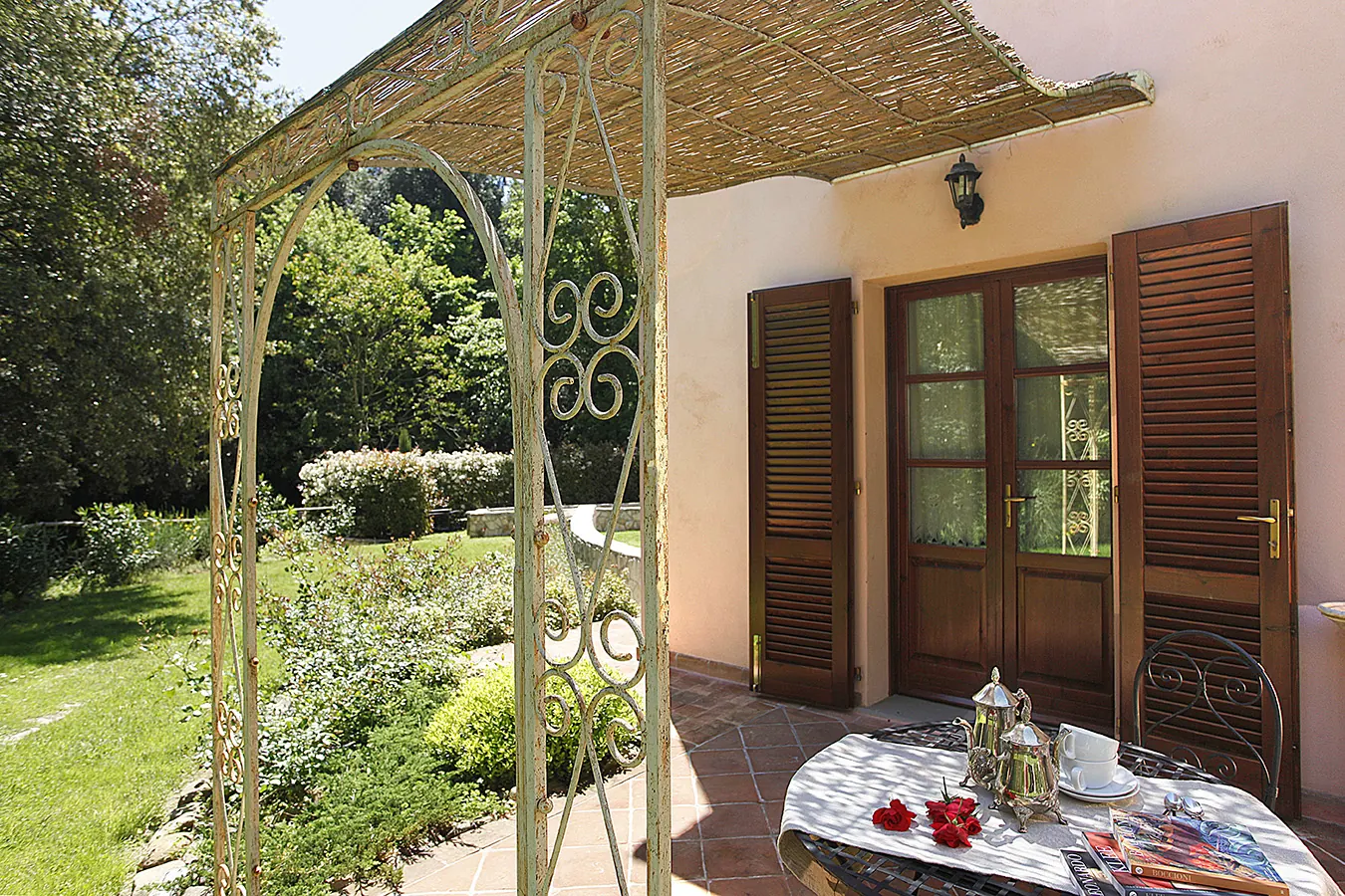 Veranda con tavolino apparecchiato davanti a una casa con giardino