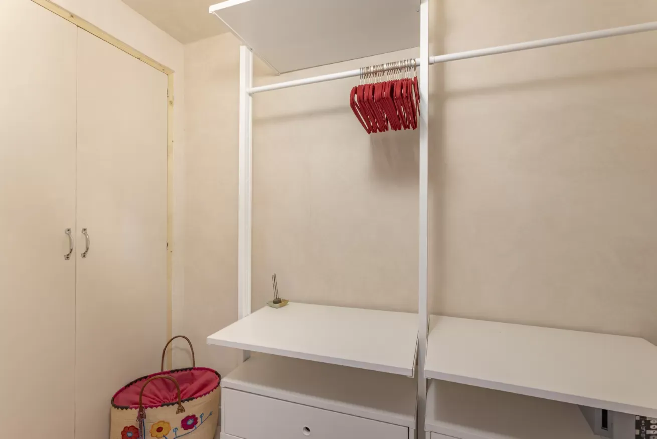 Cabina armadio vuota con ripiani bianchi e grucce rosse appese